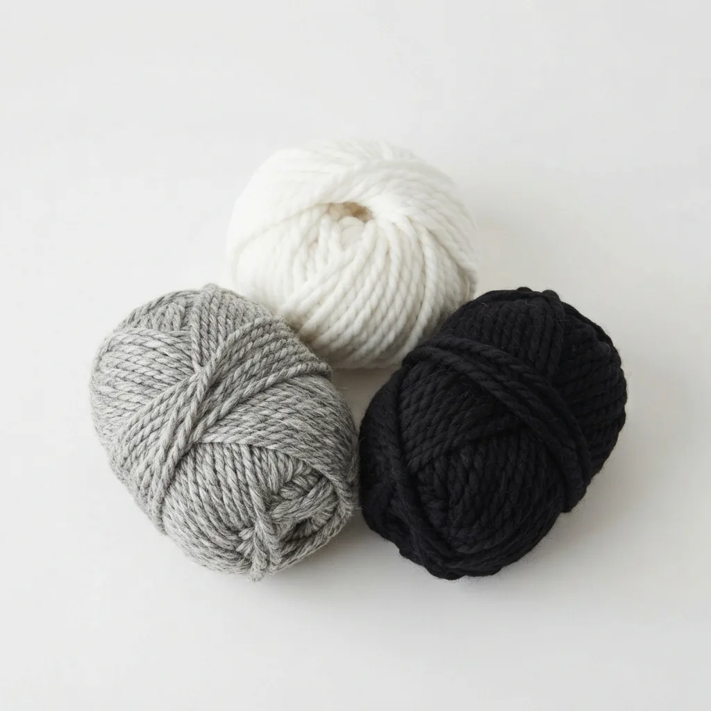 Three skeins of Loops & Threads Chunky Grande yarn in black, white, and grey.