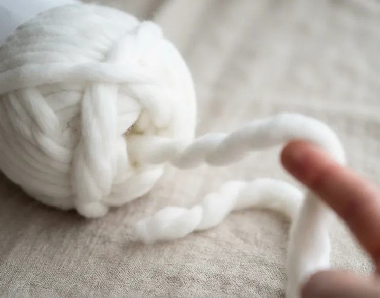 Close-up of white Free Spirit jumbo yarn being pulled from the skein for a project.